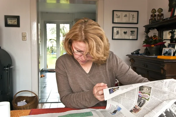 Mulher com cabelo vermelho está lendo jornal — Fotografia de Stock