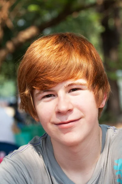 Молодой уверенный мальчик с рыжими волосами улыбается счастливо — стоковое фото