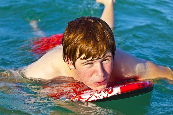 Młody chłopak jest indeksowania na deskę surfingową — Zdjęcie stockowe