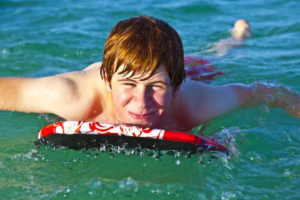 Jovem está rastejando na prancha de surf — Fotografia de Stock