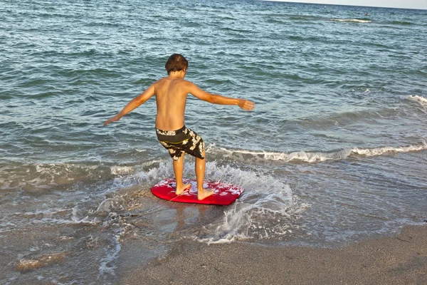 Menino aprendendo a surfar na praia — Fotografia de Stock