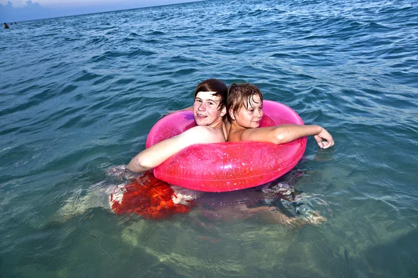 Hermanos en un anillo de natación divertirse en el océano —  Fotos de Stock