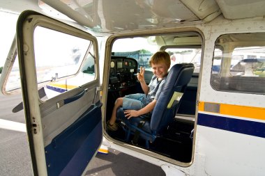 Joung boy in the pilot seat at the airport clipart