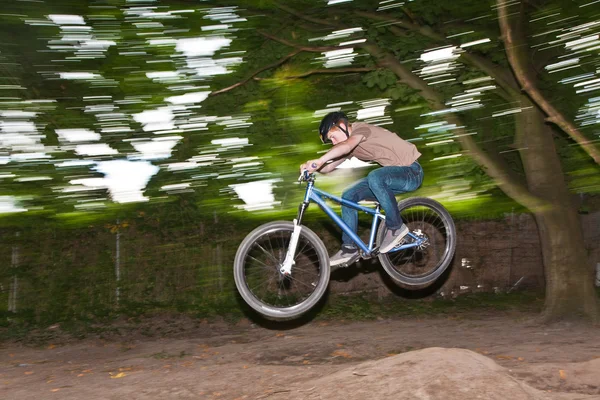 Ребенок веселится, прыгая с мотоцикла через рампу — стоковое фото