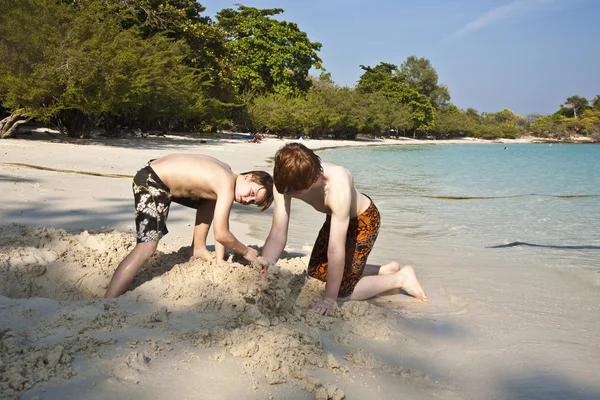 Los chicos jóvenes están disfrutando jugando en la playa y la figura del edificio —  Fotos de Stock