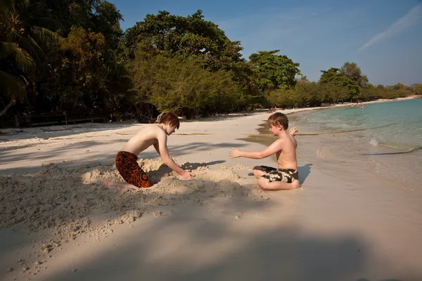 Giovani ragazzi si divertono a giocare in spiaggia e costruire figura — Foto Stock