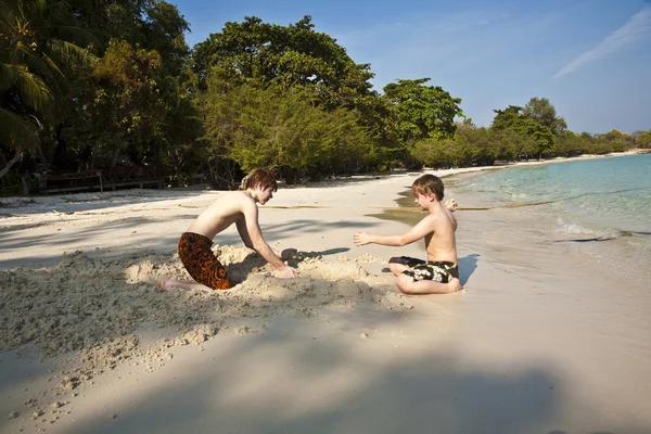 Jonge jongens genieten van spelen op het strand en het opbouwen van figuur — Stockfoto