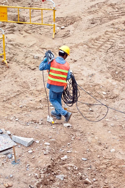 Trabalhador da construção civil que transporta um cabo eléctrico — Fotografia de Stock