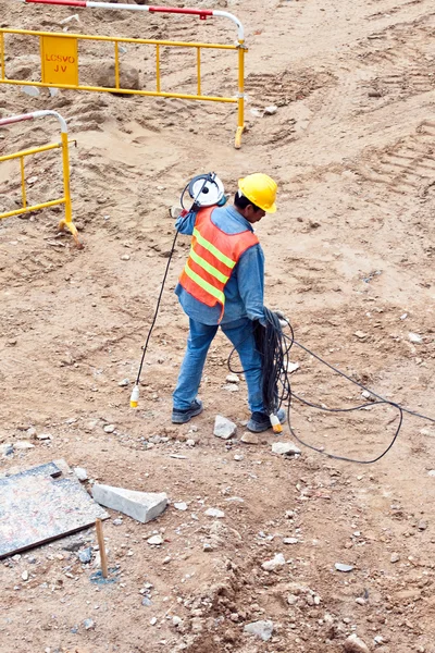 Stavební dělník na stavbě nesoucí elektrické cabl — Stock fotografie