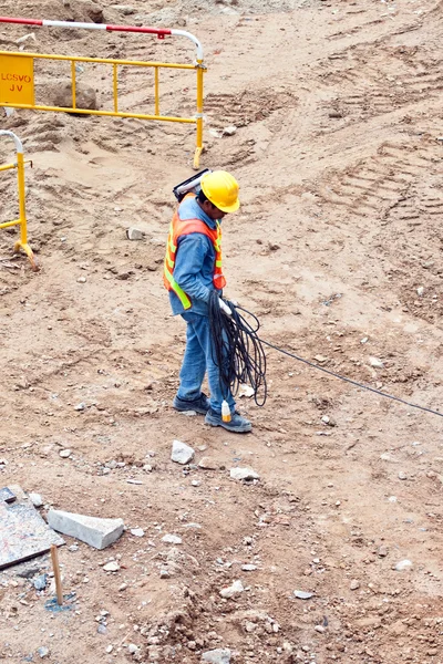 Trabalhador da construção civil que transporta um cabo eléctrico — Fotografia de Stock