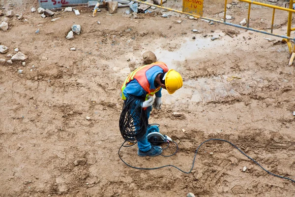Robotnik budowlany w budowie prowadzenie kabli elektrycznych — Zdjęcie stockowe