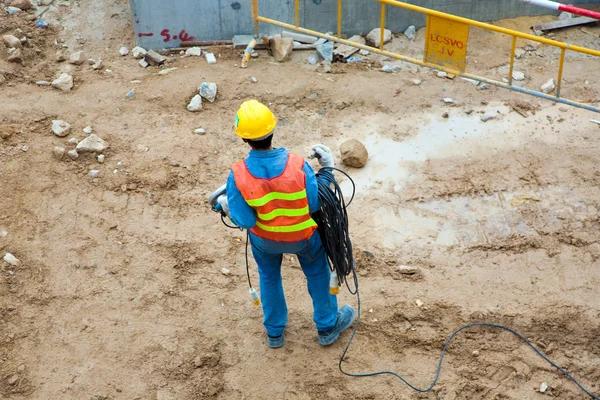 Строитель на строительной площадке с электрическим кабелем — стоковое фото