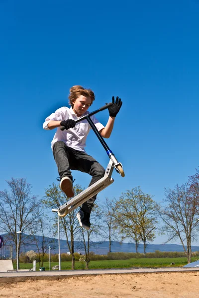Chłopiec z skuter chodzi unoszącego się w powietrzu w skate parku — Zdjęcie stockowe