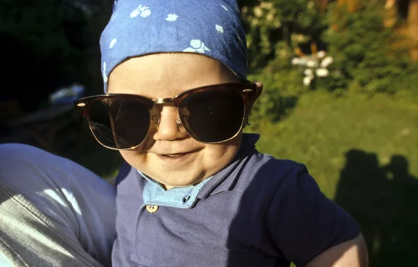 Мальчик в огромных солнцезащитных очках улыбается и счастлив — стоковое фото