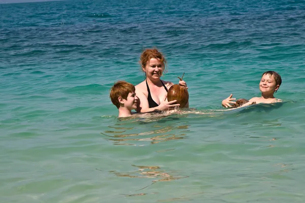 Familia está jugando con un coco en el mar en una hermosa playa —  Fotos de Stock