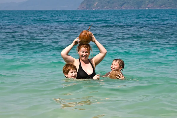 Οικογένεια παίζει με μια καρύδα στη θάλασσα σε ένα όμορφο beac — Φωτογραφία Αρχείου