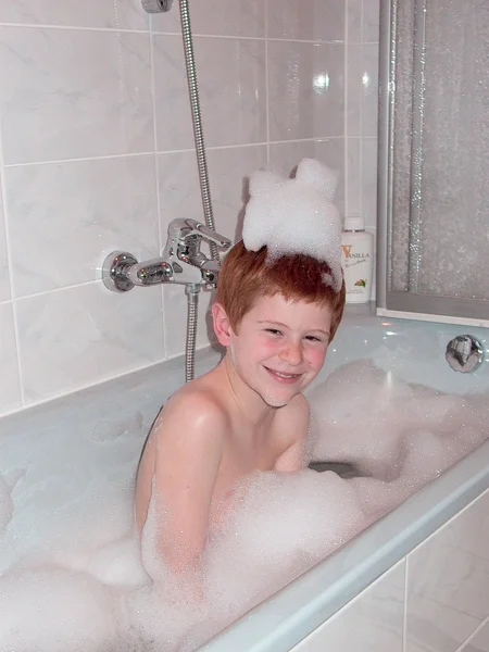 Chłopiec w rurze kąpiel z pianą na głowę — Zdjęcie stockowe