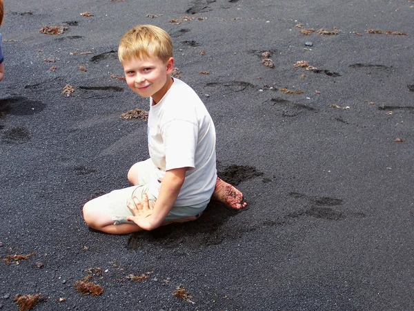 Νεαρό αγόρι κάθεται χαλαρή, χαμογελαστός και χαρούμενος στο μαύρο v — Φωτογραφία Αρχείου