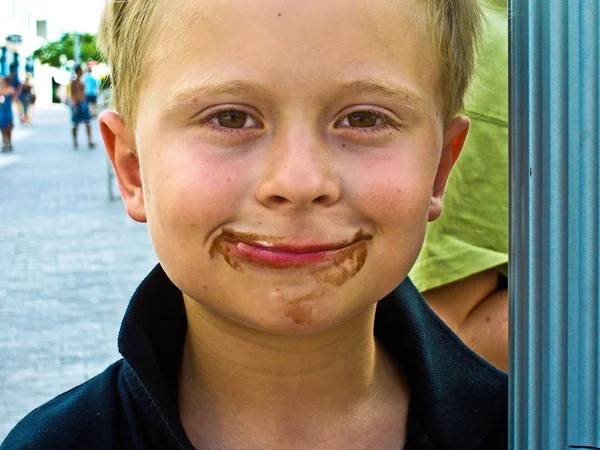 Niño tiene chocolate alrededor de su boca y sonríe — Foto de Stock