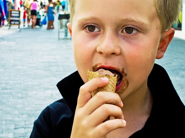 Мальчик ест мороженое и наслаждается им — стоковое фото