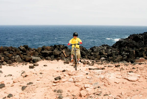 Menino montando sua mountain bike offroads e fazendo truques — Fotografia de Stock