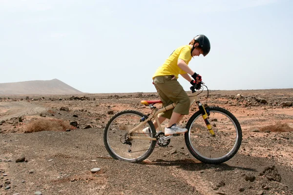 Pojke ridning hans mountainbike offroads och gör tricks — Stockfoto