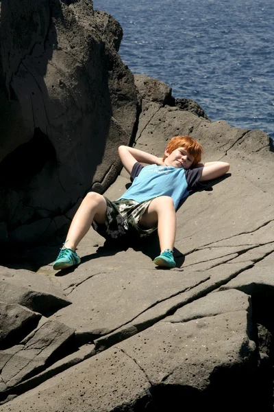 Mutlu çocuk kayanın üzerinde yer alır. — Stok fotoğraf