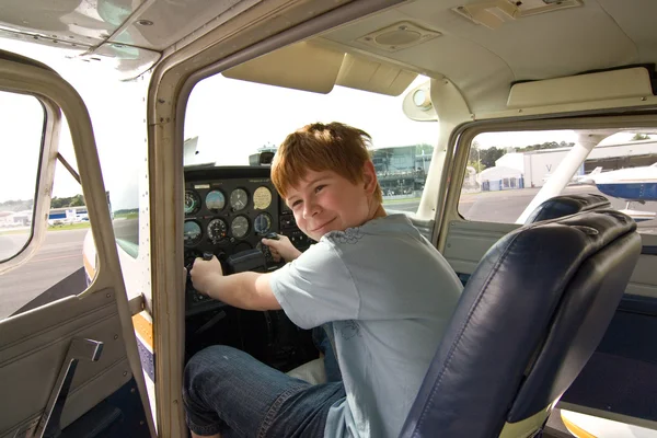 在机场的飞行员座位的庄男孩 — 图库照片