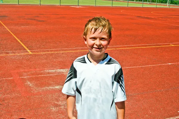Junge schwitzt beim Fußballspielen, sieht aber glücklich und selbstbewusst aus — Stockfoto