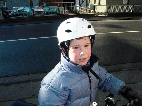 Cute boy in anorak on bike with dirt in the face from riding in — Stock Photo, Image