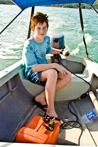 Joung pojke med rött hår styrning båten över havet — Stockfoto