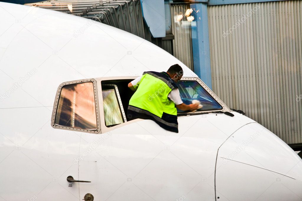 Worker is cleaning the cockpit window of an aircraft