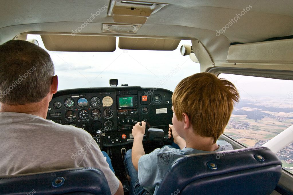 Joung boy is flying aircraft assisted by a trainer
