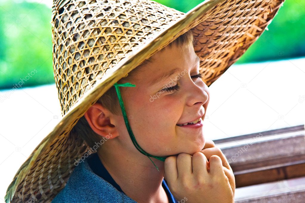 Child is wearing a hat made of bamboo during a boattrip