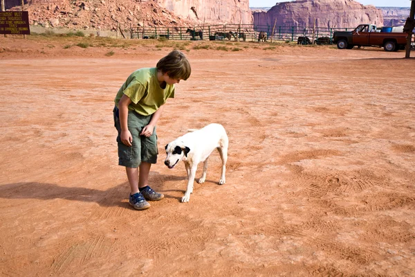 Monument Valley, boy strokes a beautiful lovely dog in the lands — Stock Photo, Image
