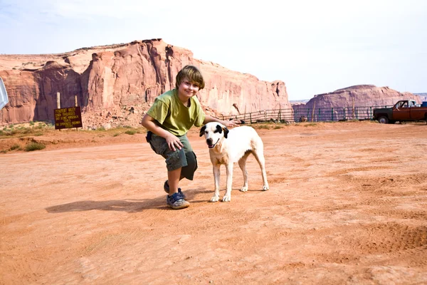 Monument valley, w chłopiec głaszcze piękna piękny pies w ziemie — Zdjęcie stockowe