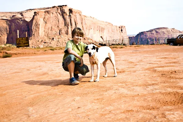 Stock image Monument Valley, boy strokes a beautiful lovely dog in the lands