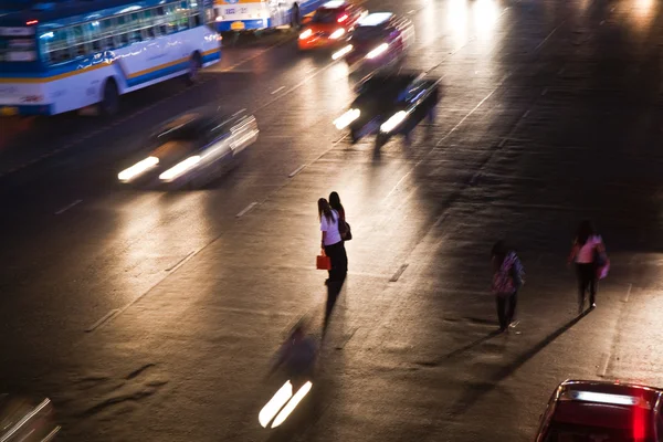 Kvinder krydser en hovedvej i Bangkok om natten - Stock-foto