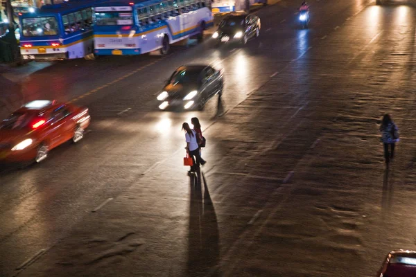 Women crossing a mainroad in Bangkok by night — Stock Photo, Image