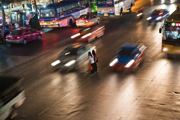 Mulheres cruzando uma estrada principal em Banguecoque à noite — Fotografia de Stock