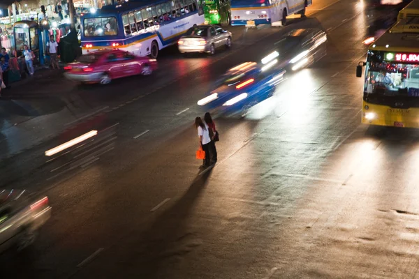 Women crossing a mainroad in Bangkok by night — Stock Photo, Image