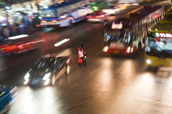 Mujeres cruzando una carretera principal en Bangkok por la noche — Foto de Stock