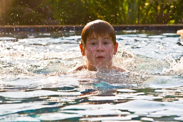 Ragazzo con i capelli rossi sta nuotando in piscina e enyoing il fresco — Foto Stock