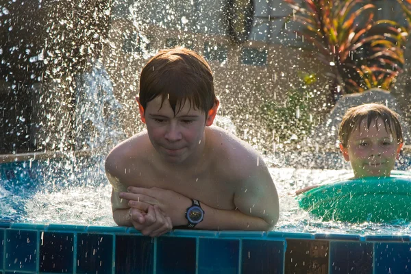 Barn leker i en pool och spottering med vatten — Stockfoto