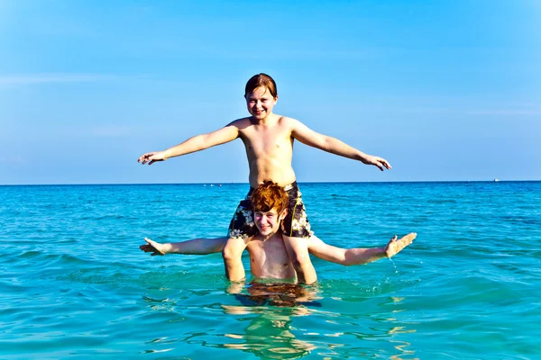 Irmãos estão desfrutando da água morna clara na bela praia e playi — Fotografia de Stock