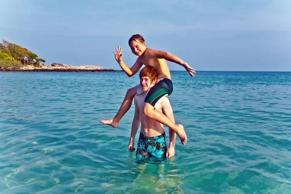Brothers are playing together in a beautiful sea with crystal clear water a — Stock Photo, Image