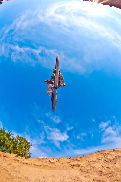 Pojken har roliga hoppa med sin dirtbike under blå himmel — Stockfoto