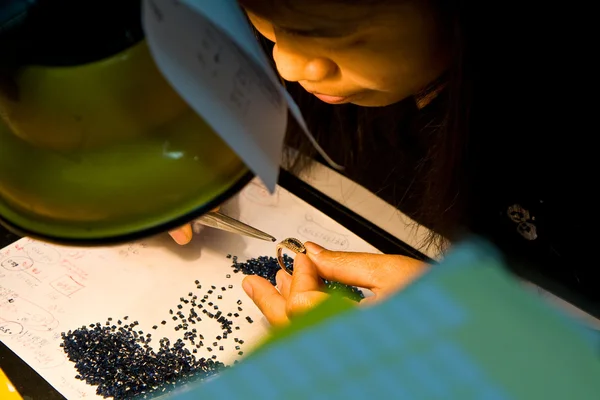 Female asian goldsmith puts jewelry into the golden ring — Stock Photo, Image