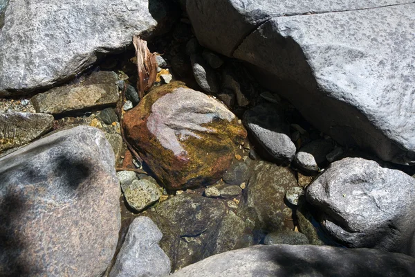 Pedras coloridas na água fria clara de um riacho com água de yosemite — Fotografia de Stock