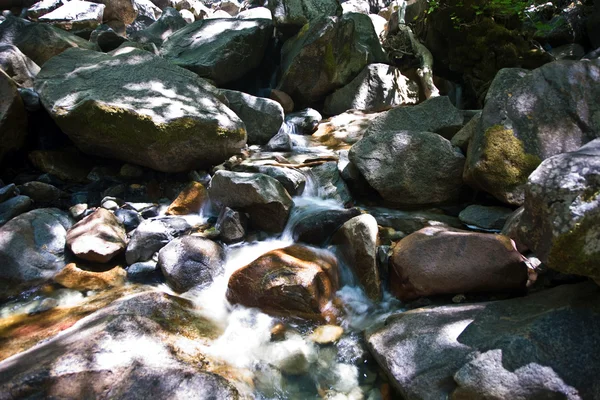 Piedras coloridas en el agua fría clara de un arroyo con agua de yosemite —  Fotos de Stock